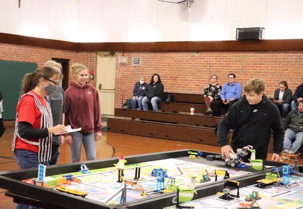 3 female students  and 1 male student standing over robotics table